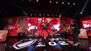 Cosplayer com armadura vermelha e asas gigantes no palco do SWC Copa Americas segurando troféu, durante evento com iluminação e cenografia.